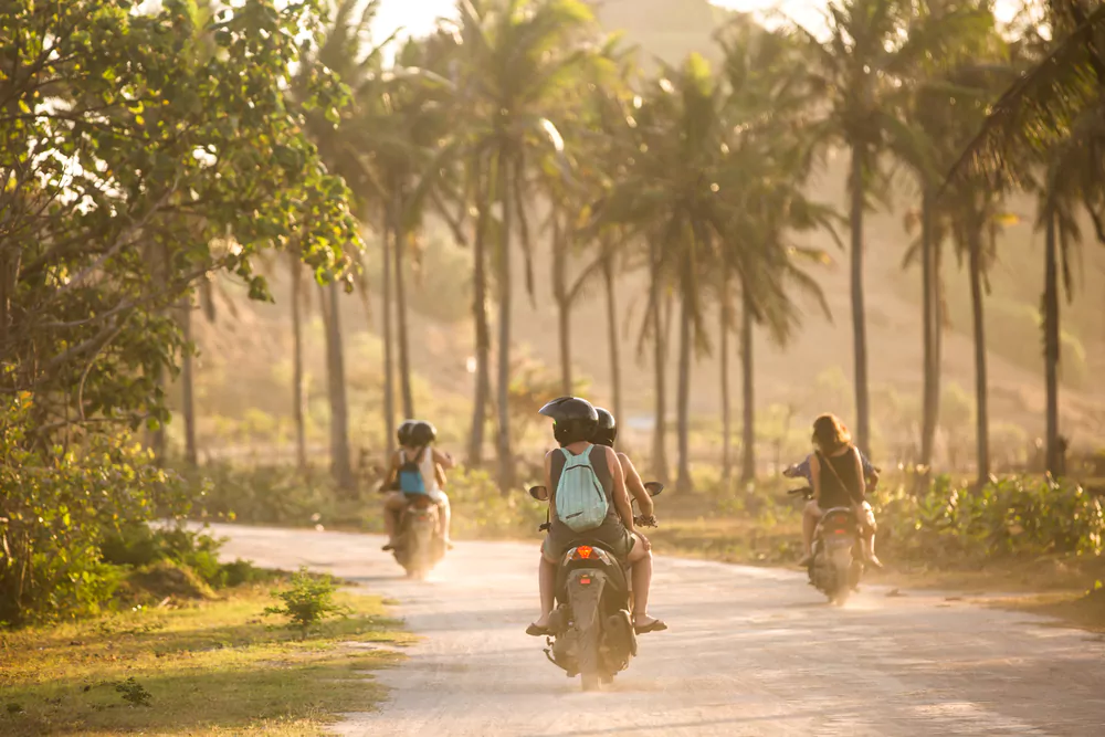 Tourist riding scooter through lush green Tegalalang rice terraces in Ubud, Bali