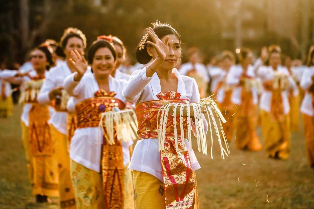 Balinese Hindu ceremony with locals in traditional dress making offerings at temple