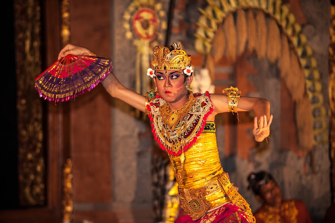 Traditional Balinese dancer performing Legong dance in ornate golden costume at temple ceremony